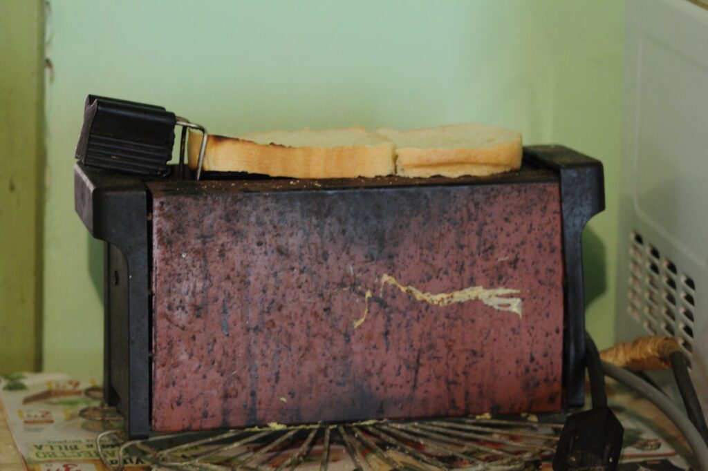 A close-up image of an old unplugged toaster with slices of bread on it.