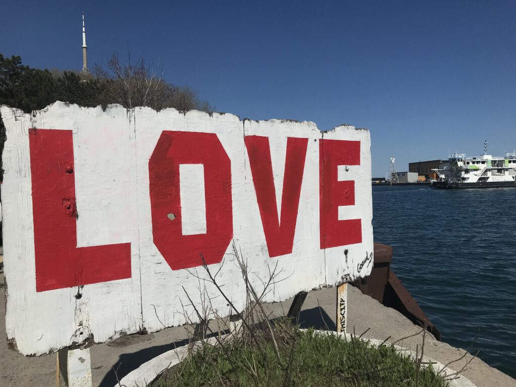 Shore of Lake Ontario, with sign that says "love" in the foreground.